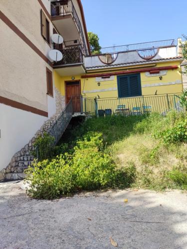 a yellow house with a staircase next to a building at casa PaMelia in Frosinone