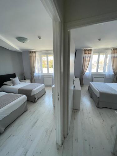 a hotel room with two beds and two windows at Hôtel de la Plage in Houlgate
