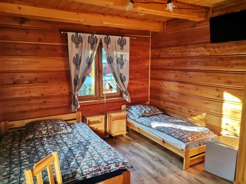 2 camas en una cabaña de madera con ventana en uDany Noclegi obok Gondoli, en Szczyrk