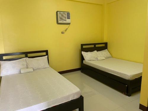 two beds in a room with yellow walls at Chamie's Transient House in Baler