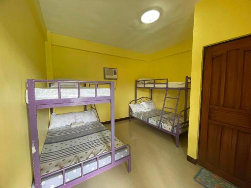 two bunk beds in a room with a yellow wall at Chamie's Transient House in Baler