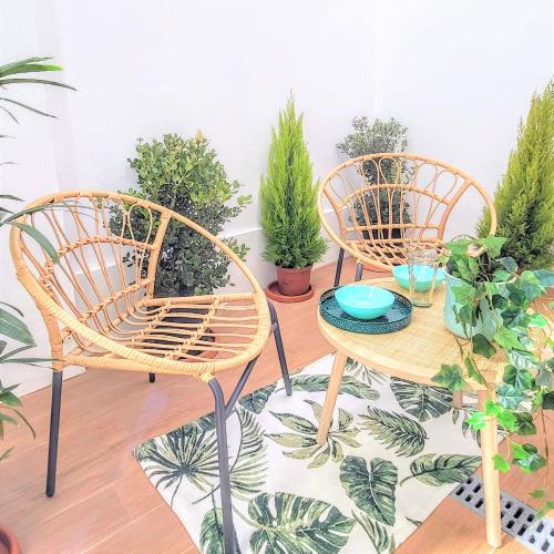two wicker chairs and a table with potted plants at The Shore at Seaside Paradise - Cozy Patio on the Promenade in Espinho