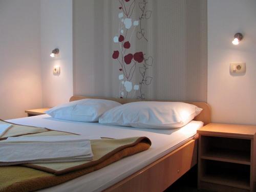 a bedroom with a bed with white sheets and pillows at Pansion Nikica Kozina in Međugorje
