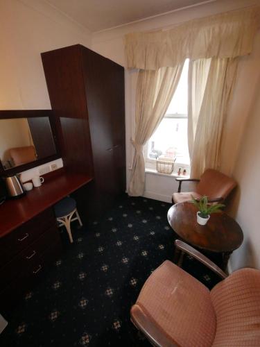 a hotel room with a chair and a table and a window at Bourne Hall Hotel in Bournemouth