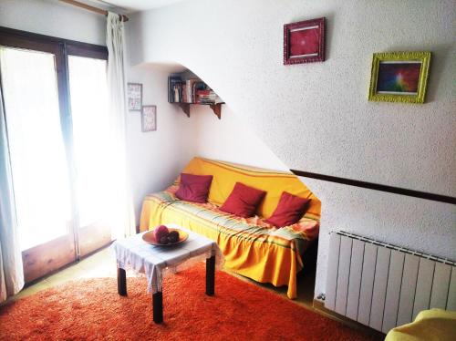 ein Schlafzimmer mit einem Bett mit einer orangefarbenen Decke und einem Tisch in der Unterkunft Apartament Rural Vilaplana in Vilaplana