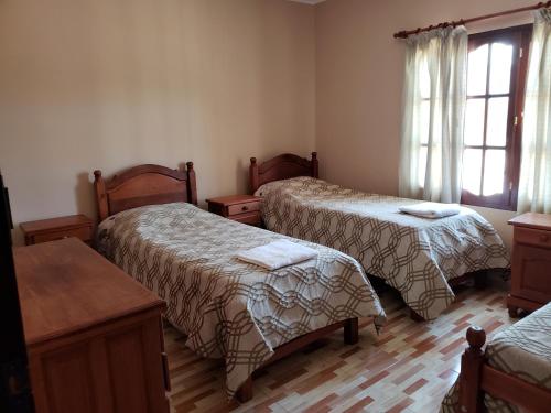 Zimmer mit 3 Betten, einem Tisch und einem Fenster in der Unterkunft Casa Piedra Blanca in Cachí