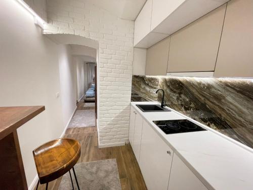 cocina con armarios blancos, fregadero y taburete en Colorway Apartment en Belgrado