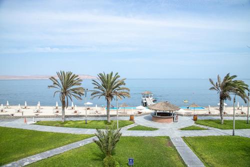a view of a beach with palm trees and a gazebo at Condominio Nuevo Paracas in Paracas