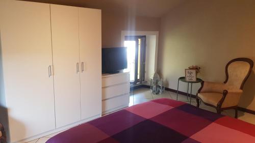 a bedroom with a bed and a tv and a chair at Ca di Biella in Biella