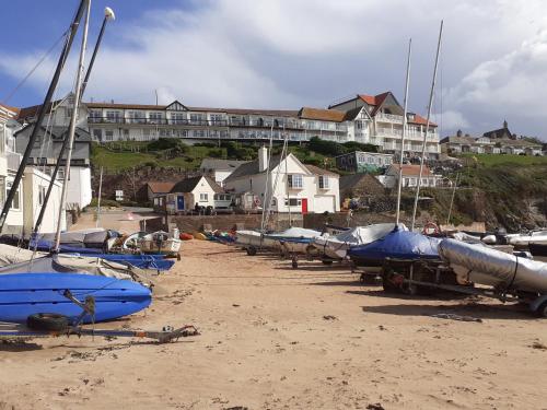 a row of boats sitting on the beach with buildings in the background at The Cottage Hotel in Hope-Cove