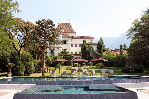 a resort with a pool and chairs and a building at Hotel Castel Rundegg (Adults Only) in Merano
