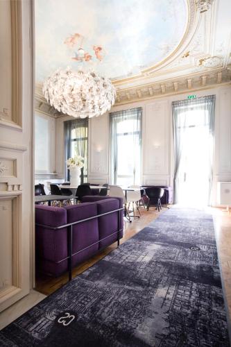 a living room with purple furniture and a chandelier at Hotel C2 in Marseille