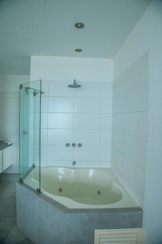 a bath tub with a glass shower in a bathroom at Condominio Nuevo Paracas in Paracas