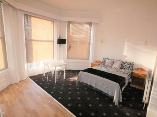 a bedroom with a bed and a table and windows at Bourne Hall Hotel in Bournemouth