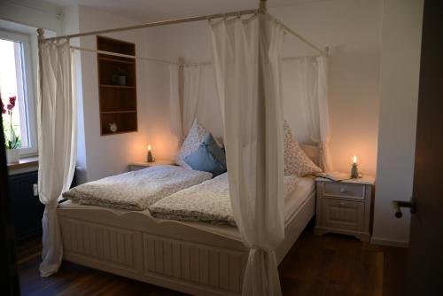 ein Schlafzimmer mit einem Himmelbett mit Vorhängen und einem Fenster in der Unterkunft Ferienwohnung Die Alte Schule in Daun
