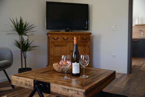 a bottle of wine and two glasses on a wooden table at Ferienwohnung Die Alte Schule in Daun
