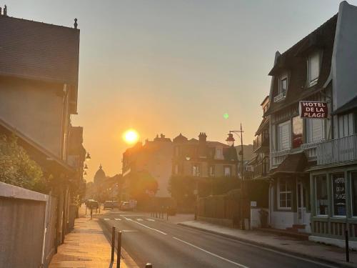 a city street with the sun setting in the distance at Hôtel de la Plage in Houlgate