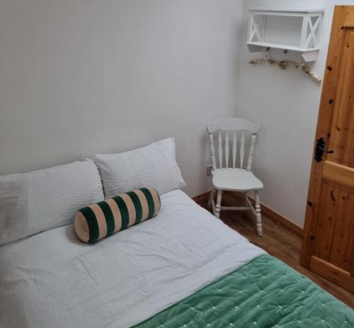 a bed with a pillow on it with a chair at Be's Cottage in Malin Head