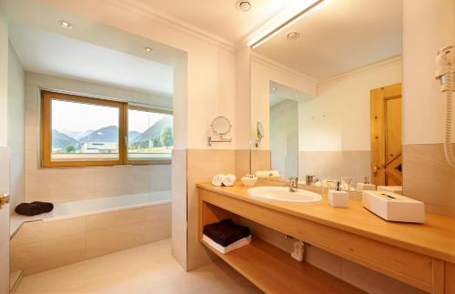 uma casa de banho com um lavatório e um espelho grande em Hotel Waidmannsheil em Flachau