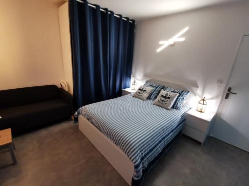 - une petite chambre avec un lit et un rideau bleu dans l'établissement Appartement Azur, à Balaruc-les-Bains