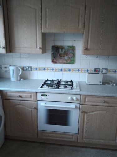 a kitchen with a white stove and wooden cabinets at 1 Double room with shared bathroom in Bracknell