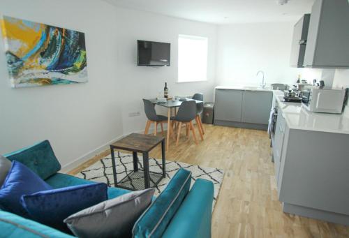 sala de estar con sofá azul y cocina en The Swell - Avondale One Bed, en Rhosneigr