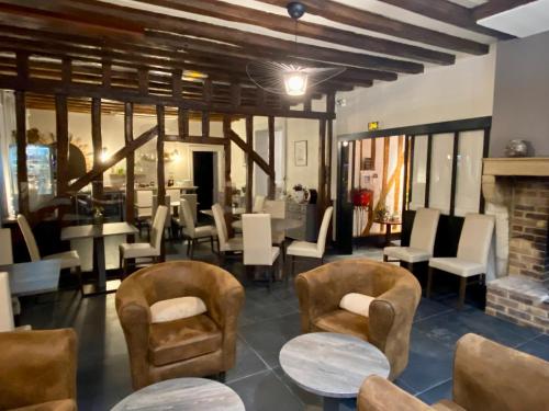 a restaurant with chairs and tables and a fireplace at Logis Hostellerie la Chaumière in Arsonval