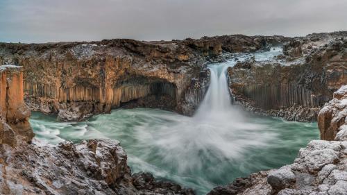 a waterfall in a canyon in the snow at Fljótsbakki Hotel in Godafoss