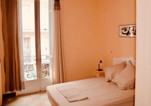 une chambre avec un lit et une grande fenêtre dans l'établissement Appartement 2 Les Clématites, à Menton