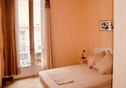 um quarto com uma cama e uma grande janela em Appartement 2 Les Clématites em Menton