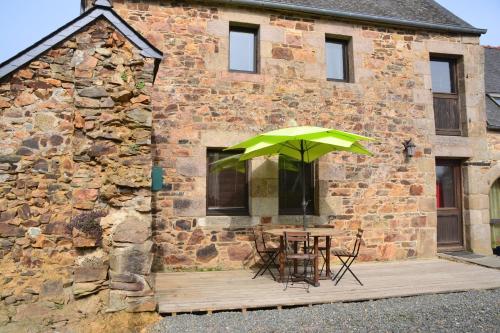 a table with a green umbrella in front of a building at Gite Gloria in Lannion