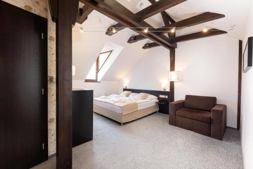 a bedroom with a bed and a chair at Bazilika alatt Panzió in Esztergom