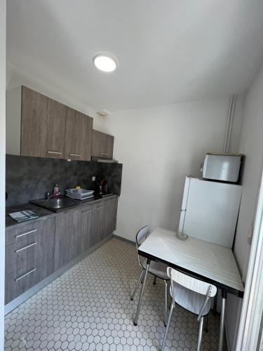 a small kitchen with a table and a refrigerator at Résidence Les Milandes in Cazaubon