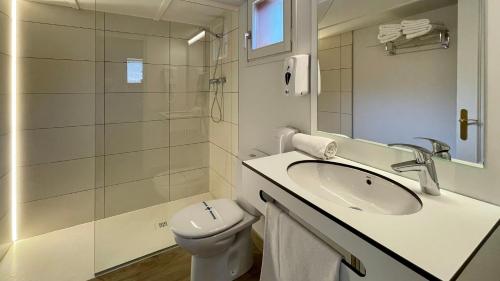 uma casa de banho branca com um lavatório e um WC em Berga Resort em Berga