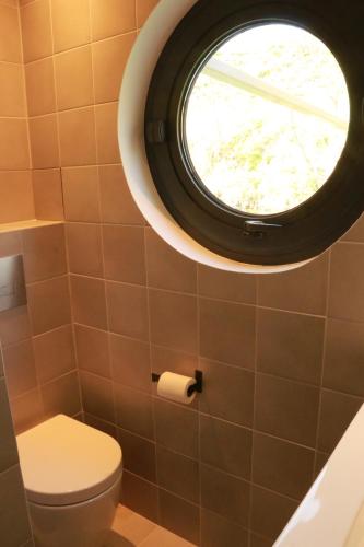 a bathroom with a toilet and a round window at Studio très cosy - indépendant dans une péniche - Paris 16 in Puteaux