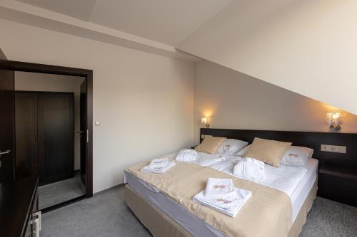 a bedroom with a large bed with towels on it at Bazilika alatt Panzió in Esztergom
