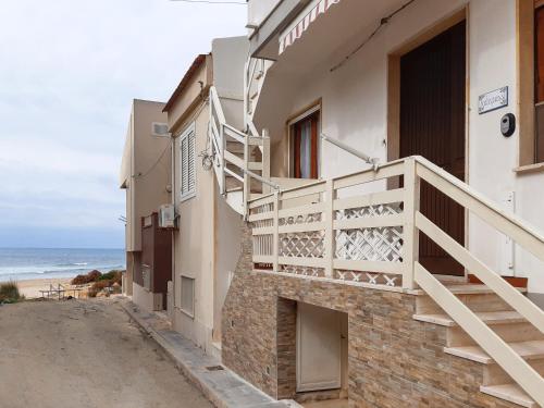 un bâtiment avec des escaliers et l'océan en arrière-plan dans l'établissement sedicipassi, à Villaggio Azzurro
