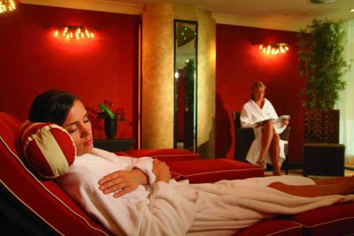 a woman laying in a bed in a room at Maritim Seehotel Timmendorfer Strand in Timmendorfer Strand