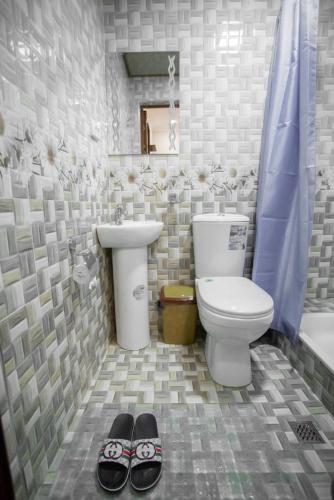 un bagno con un water, un lavandino e un paio di pantofole di Samarkand Hotel a Samarkand