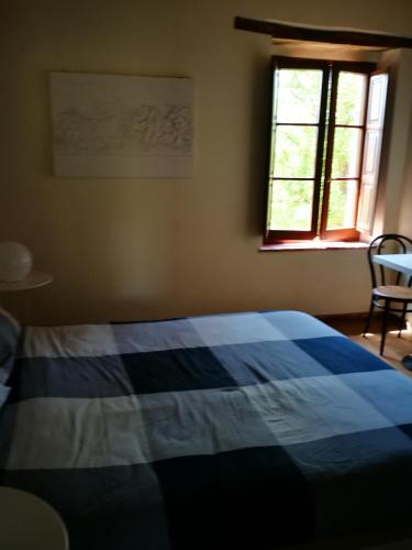 a blue and white bed in a bedroom with a window at Molino della Tuoma in San Quirico dʼOrcia