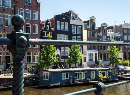 a blue house on the water in a canal with buildings at Max Brown Hotel Canal District in Amsterdam