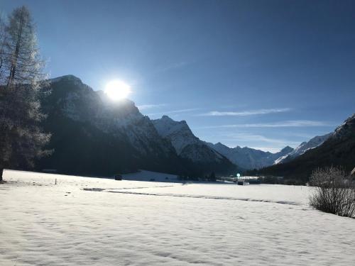 a snow covered field with the sun on a mountain at Katja´s Ferienwohnung in Trins