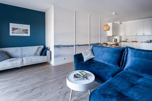 a living room with a blue couch and a table at Apartament Baltic Sea Gate Porta Mare 55m2 in Dziwnówek