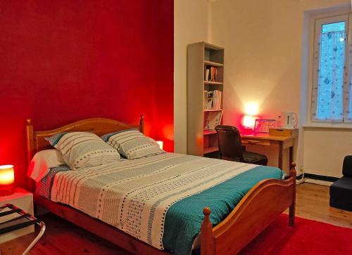 ein Schlafzimmer mit einem Bett mit einer roten Wand in der Unterkunft Le Pitstop in Alan