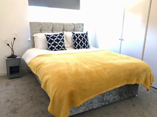a bedroom with a bed with a yellow blanket on it at Stanford Villa in Stanford-le-Hope