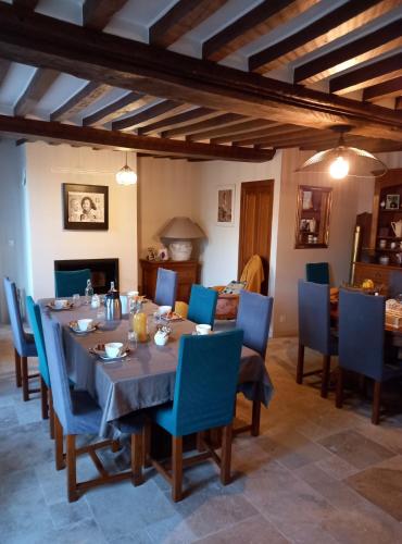 a dining room with a table and blue chairs at Ferme du Rupalley in Isigny-sur-Mer