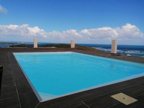 a blue swimming pool with the ocean in the background at DV Real Philoxénia in Saint Martin