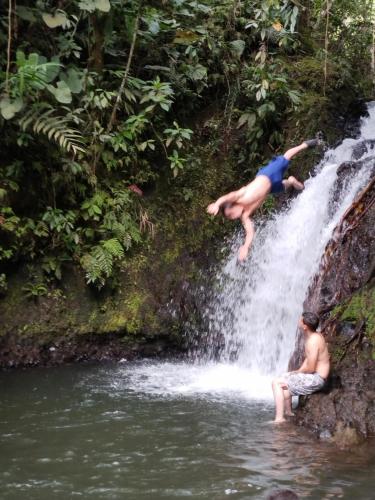 a person jumping off a waterfall into a river at Alojamiento EL GITANO in Filandia