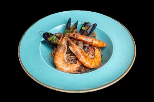 a blue plate of food with shrimp and vegetables at Hotel Relax Craiova in Craiova