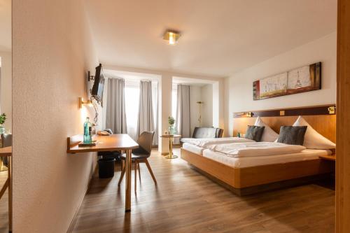 ヘスバッハにあるHotel & Restaurant Zum Ochsen -Ox Distilleryのベッドとテーブルが備わるホテルルームです。